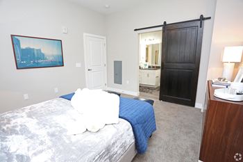 a bedroom with a bed and a sliding door to a bathroom at Century Baxter Avenue, Louisville, KY 40204